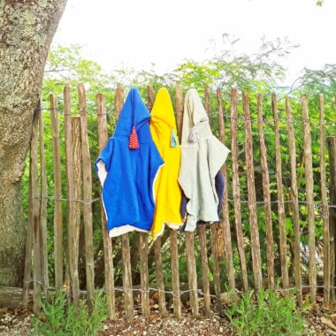 ponchos de bain pendus sur une barrière de plage en ganivelle