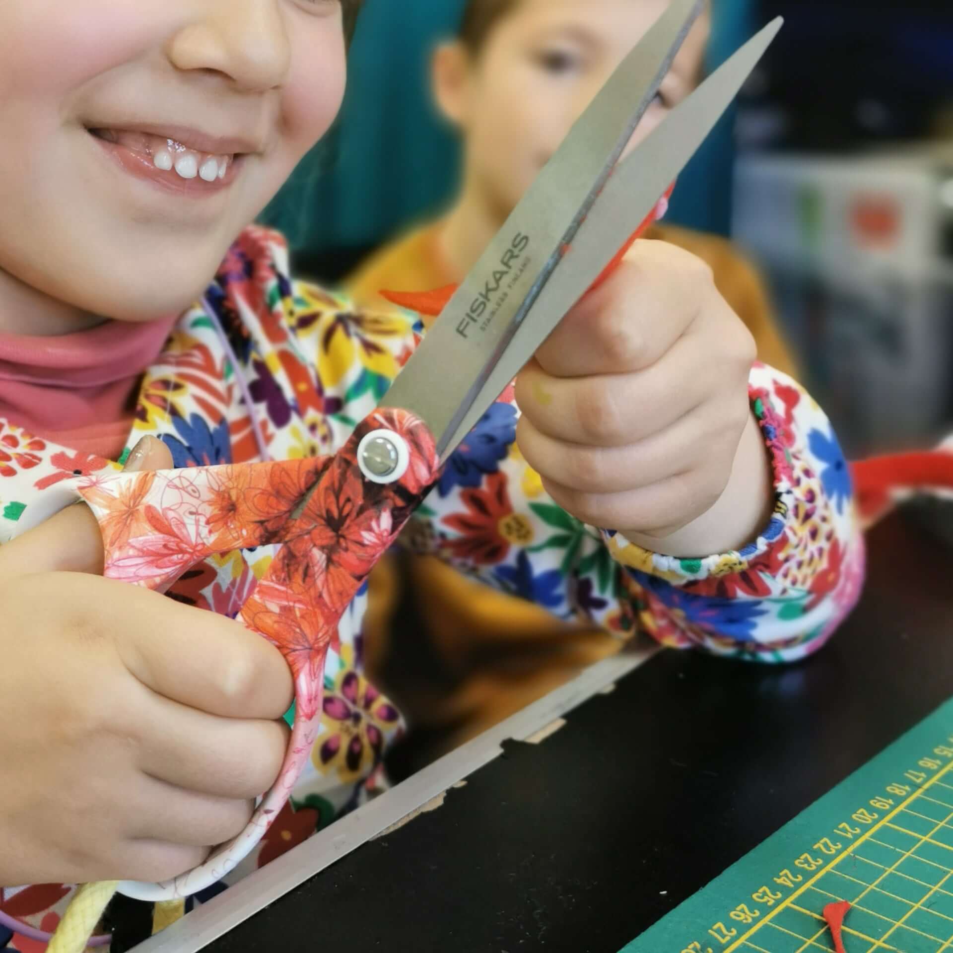 atelier couture fillette en train de découper un morceau de tissu